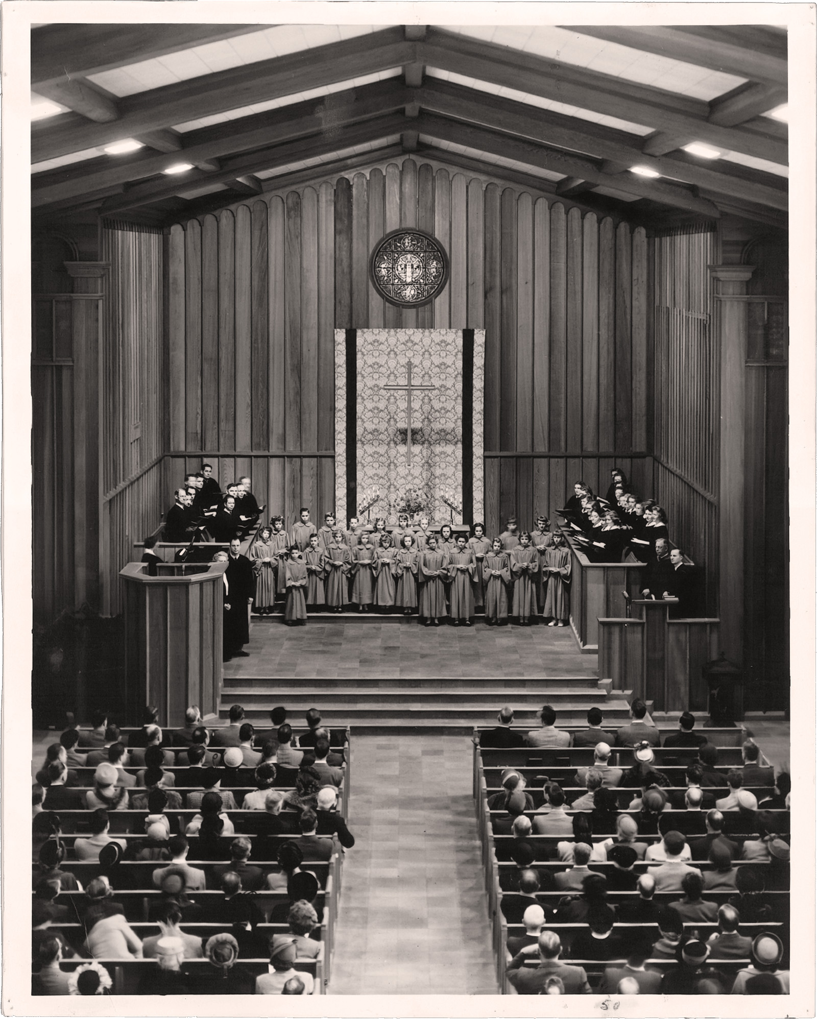 Black and white photograph circa 1950s of a worship service inside First Congregational Church of Fresno, showing a robed youth choir at the chancel before a full congregation